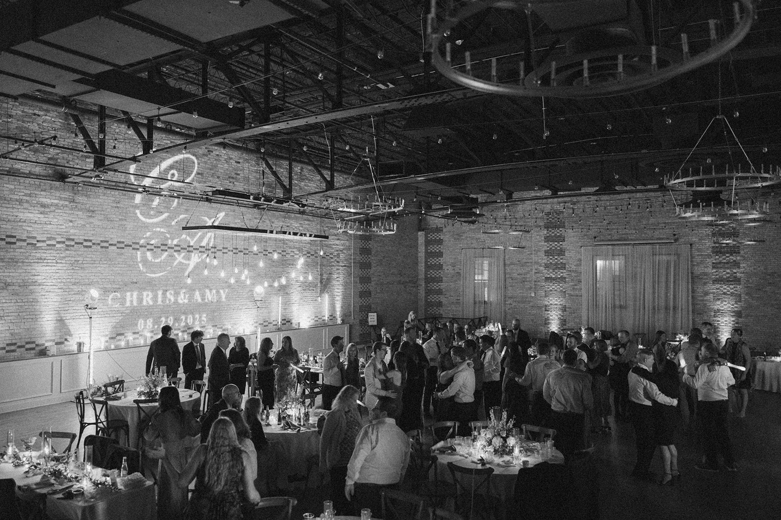 Black and white photo of a wedding reception at 10 South wedding venue, featuring guests enjoying the celebration.

