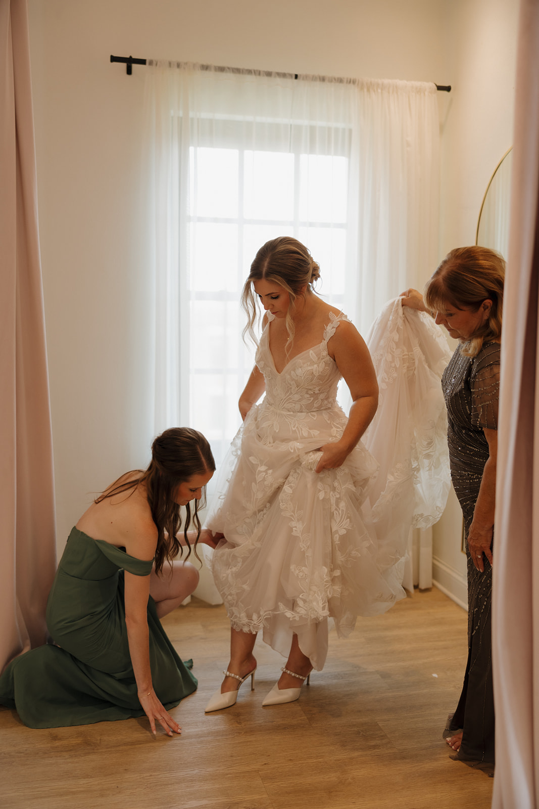Bride surrounded by friends, laughing and getting ready for her big day with hair and makeup.