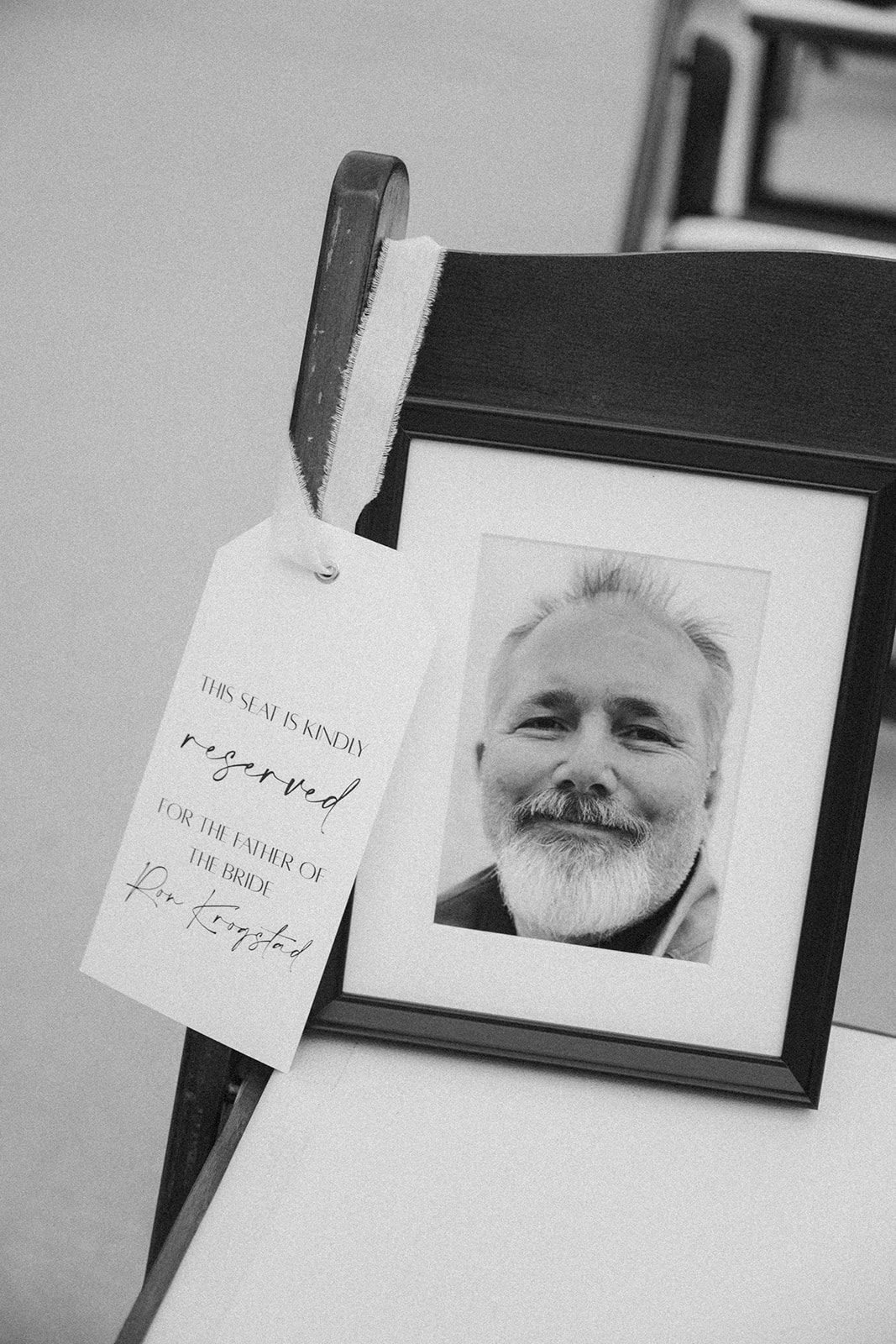 Close up of picture of bride's father in frame on a chair saving a seat for him. 