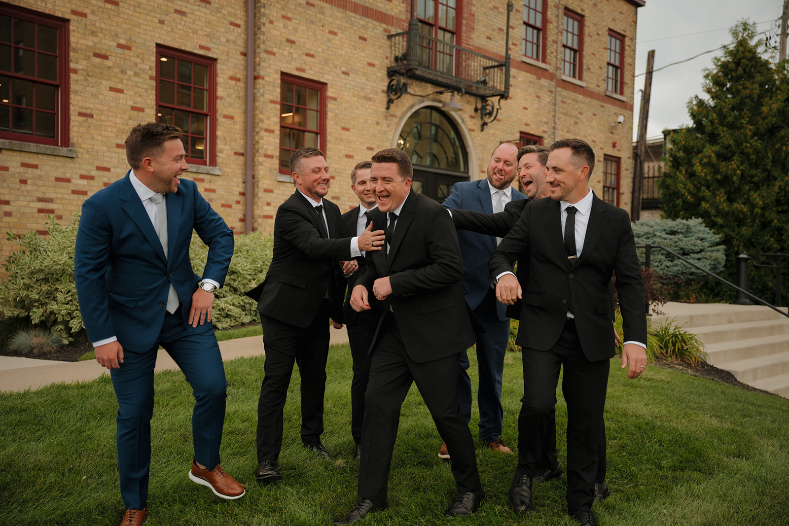 Groom and groomsmen joke together during outdoor wedding party photos at 10 South wedding venue