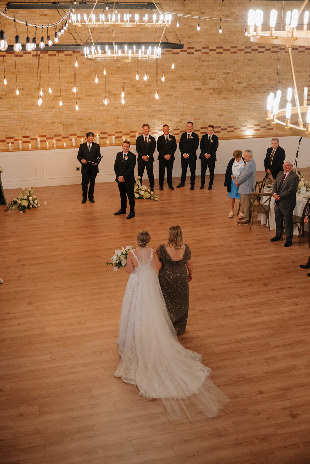 The bride and and her mother stroll down the aisle, towards her groom on her wedding day