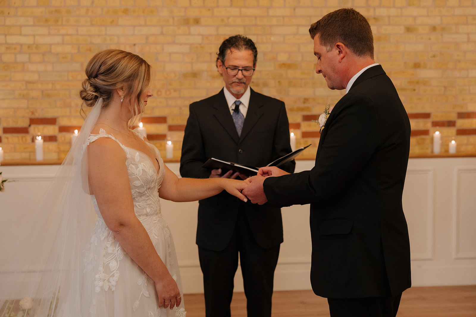 Groom places wedding band on bride's ring finger during ceremony at 10 South wedding venue in Wisconsin 