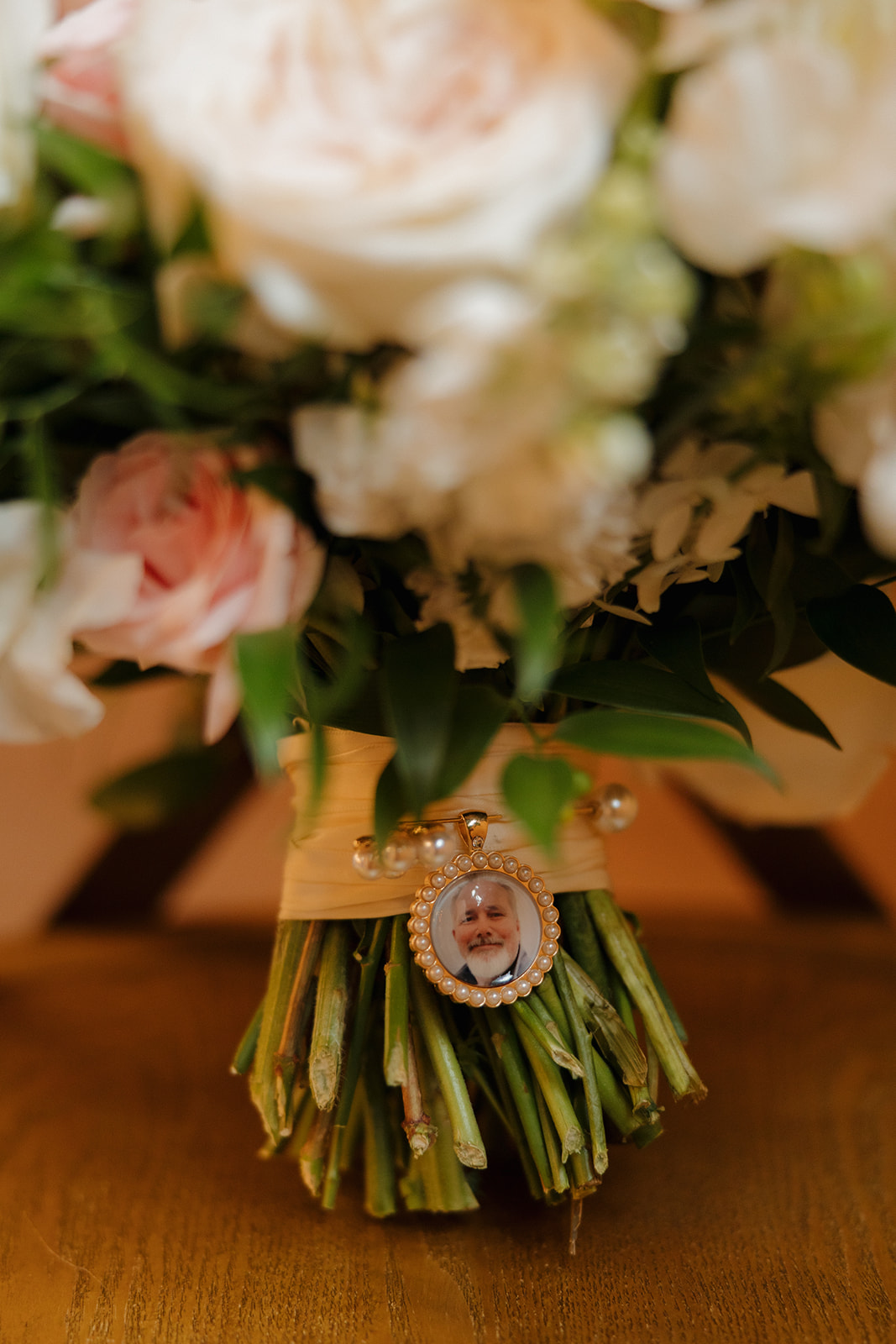 Close up of bridal bouquet featuring white and pink florals with a bouquet charm of bride's father who passed away 