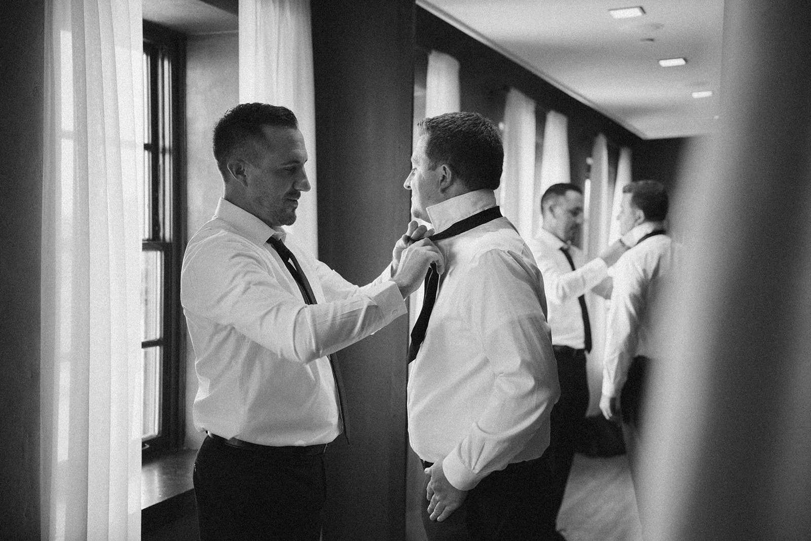 man helping groom tie his tie before wedding at 10 south wedding venue in wi 