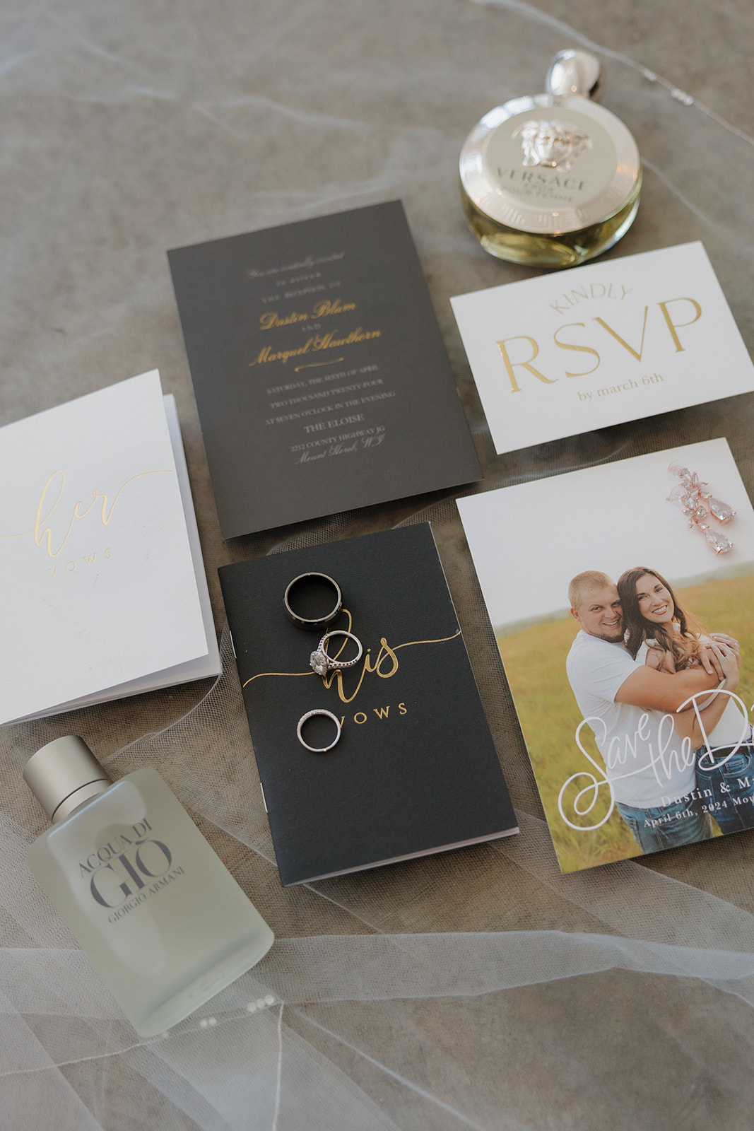 Elegant flat lay of wedding details featuring vow books, invitation suite, rings, perfume, and a save-the-date—all styled on soft tulle by a madison wedding photographer.