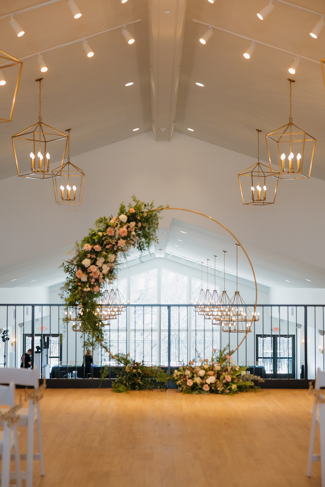 Asymmetrical floral arch with blush, white, and greenery details set against a modern chapel interior—perfect ceremony focal point.