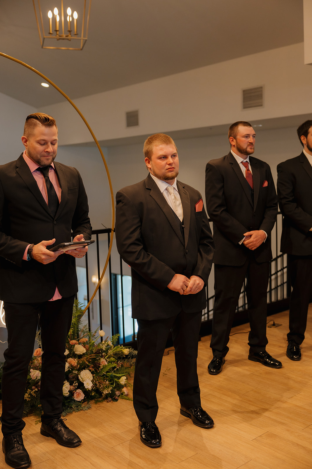 Groom stands at the altar with groomsmen lined behind him, waiting with emotion as the ceremony begins.