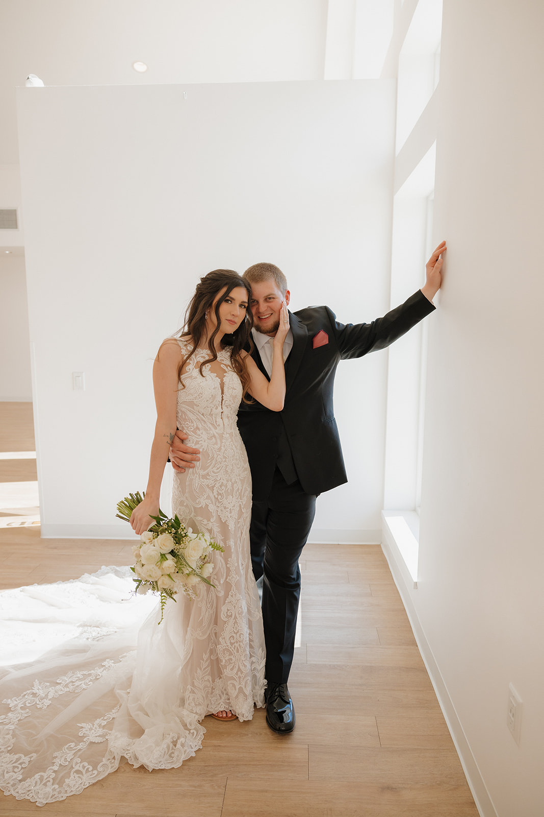 Bride leans into groom in a bright, minimalist space with natural window light—madison wedding photographer captures the quiet elegance of the moment.
