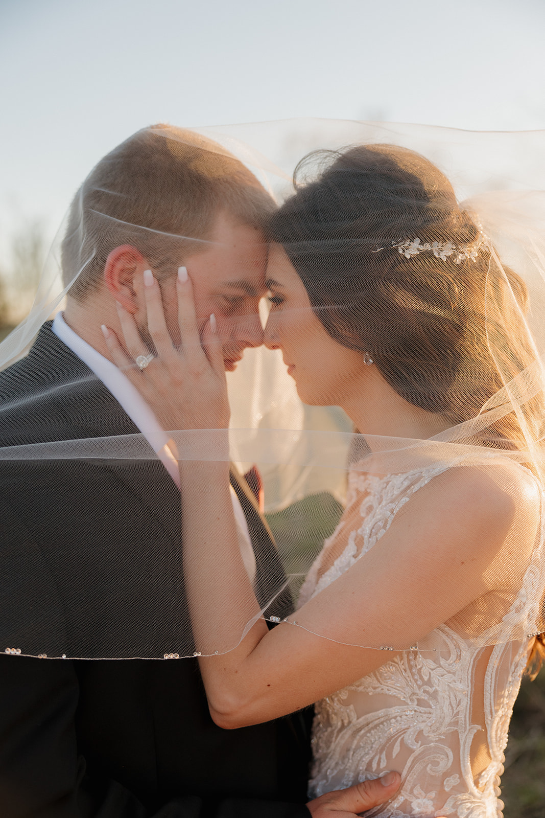 Bride and groom forehead to forehead under her veil, sharing an intimate moment with golden light illuminating their expressions—madison wedding photographer captures the quiet magic.
