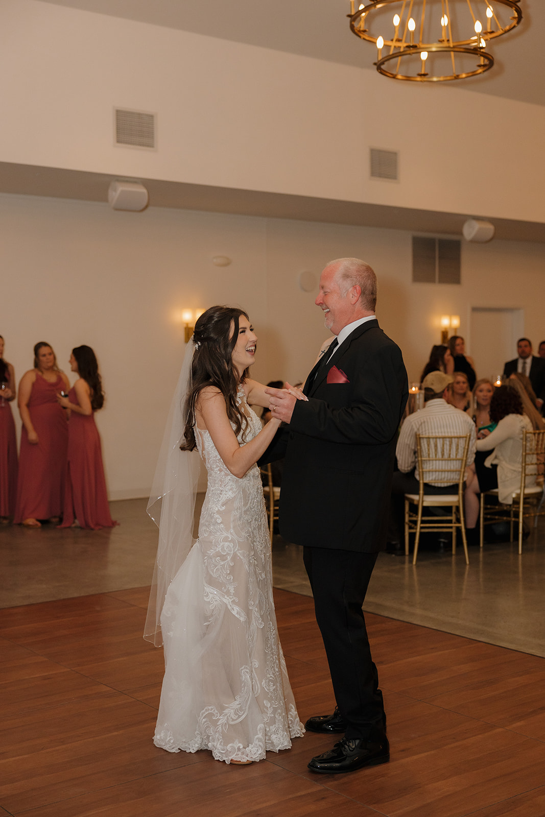 Bride dances with her father, both smiling big as guests look on—classic reception magic captured by a madison wedding photographer.