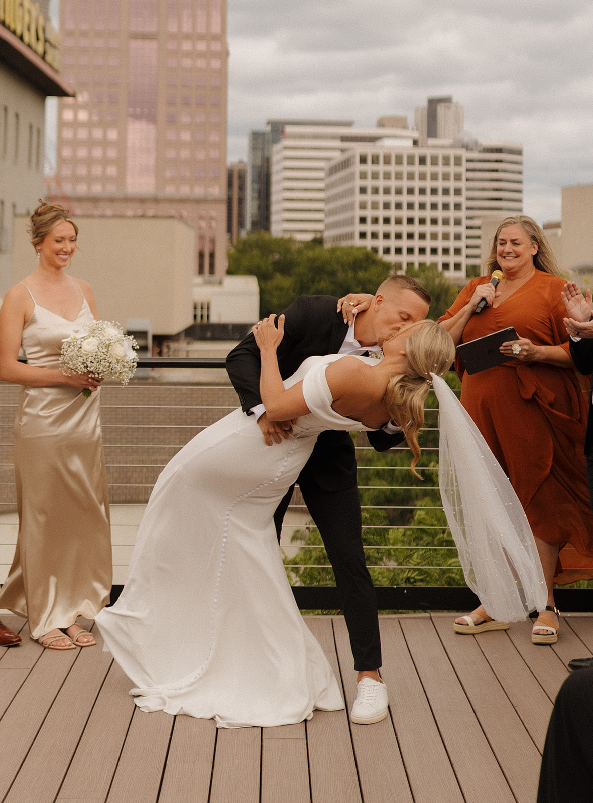Groom kisses bride in a dip kiss after intimate wedding ceremony on rooftop in Downtown Wisconsin