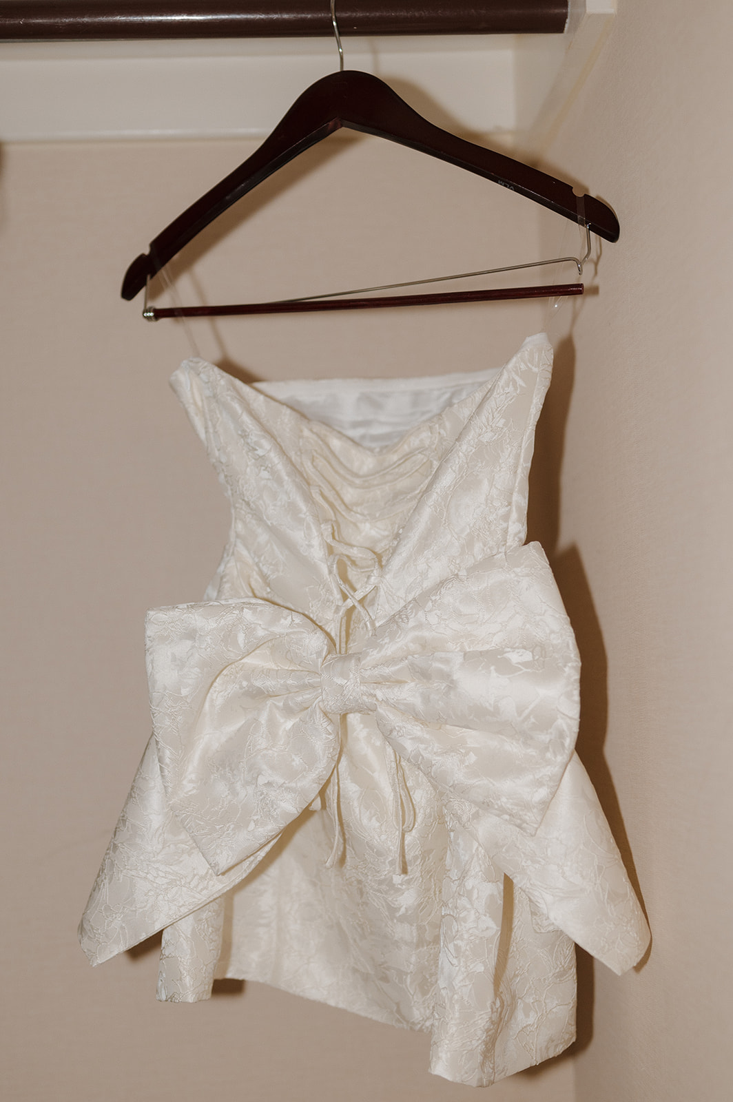 Bride's reception dress with giant bow on the back hangs on hanger