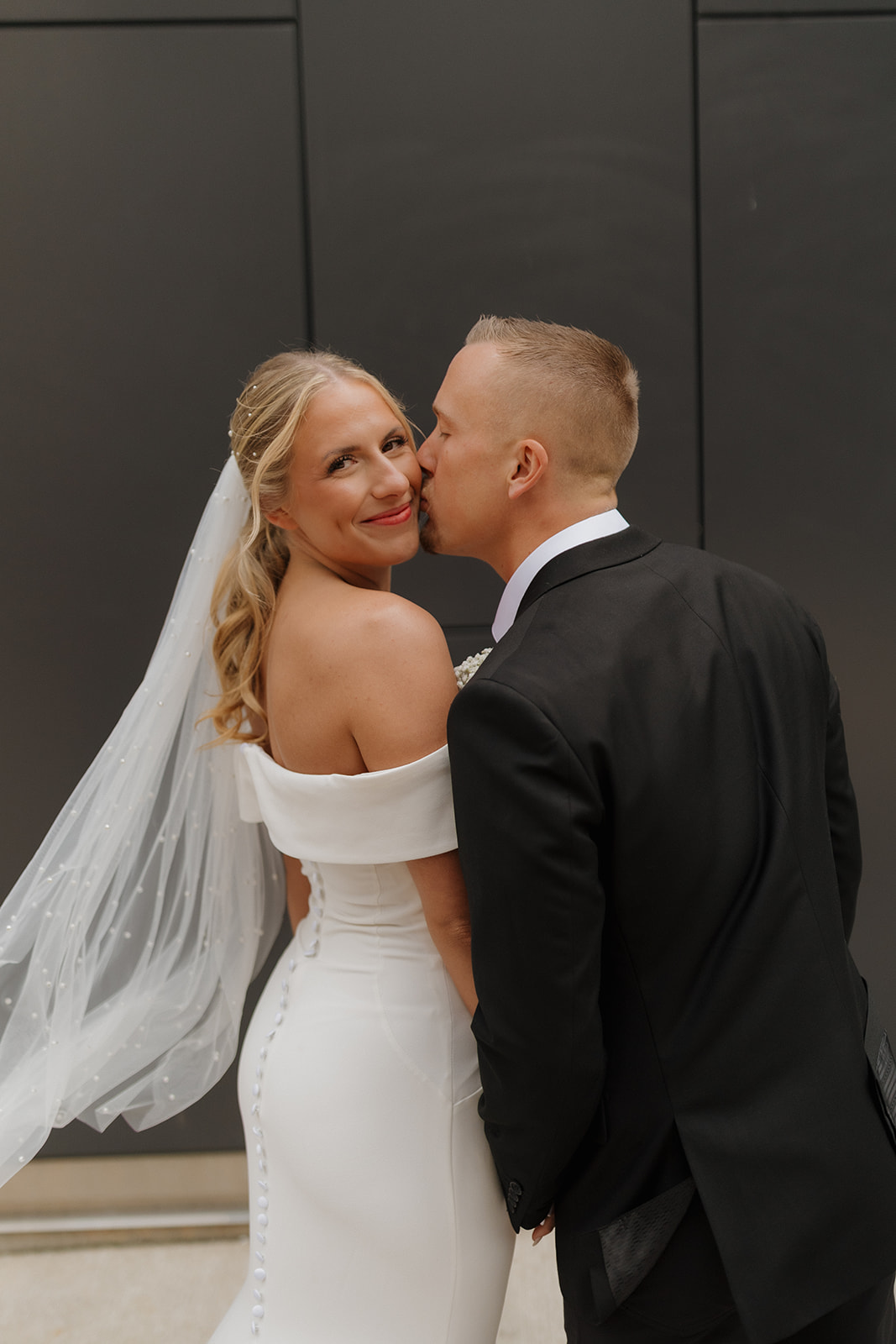 Groom kisses bride's cheek during outdoor bridal portraits after wedding in Wisconsin