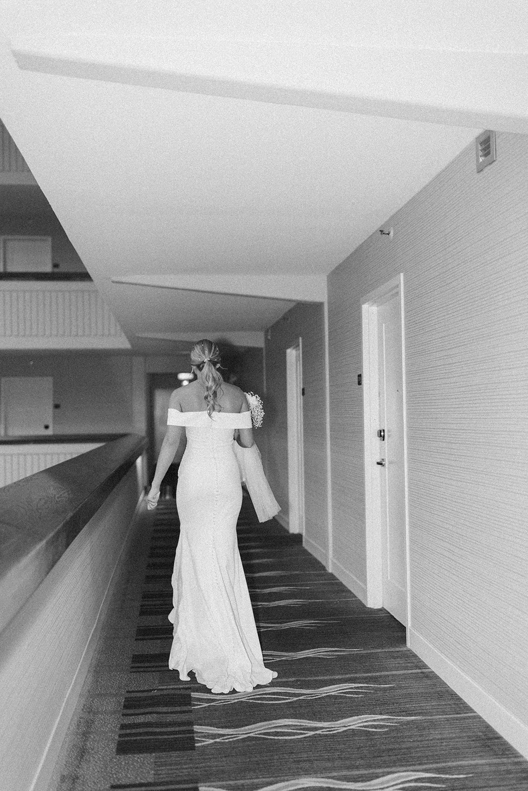 Bride holding baby's breath bouquet walking to their hotel room for her outfit change before their reception to celebrate!