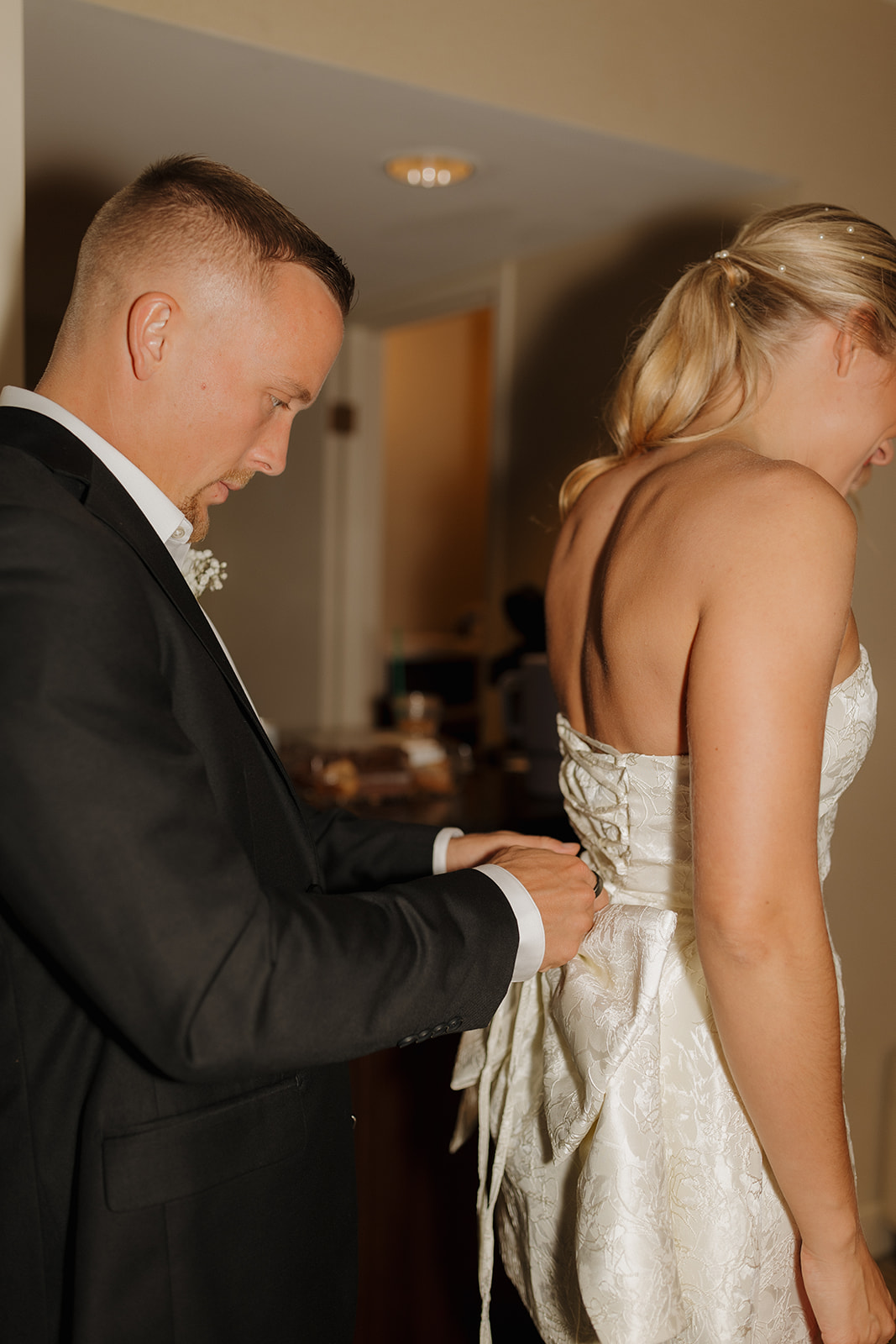 Groom puts bow on bride's reception dress in private hotel moment before joining the party