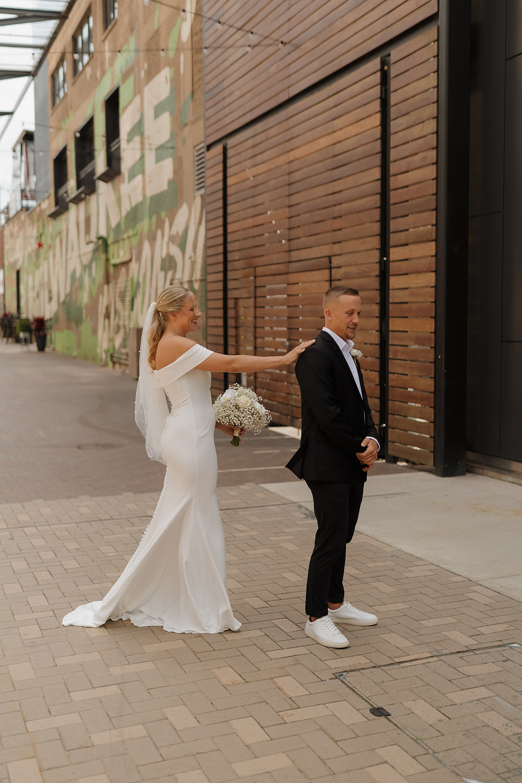 Bride playfully reaching to tap her groom’s shoulder during their first look at a wedding in Wisconsin.
