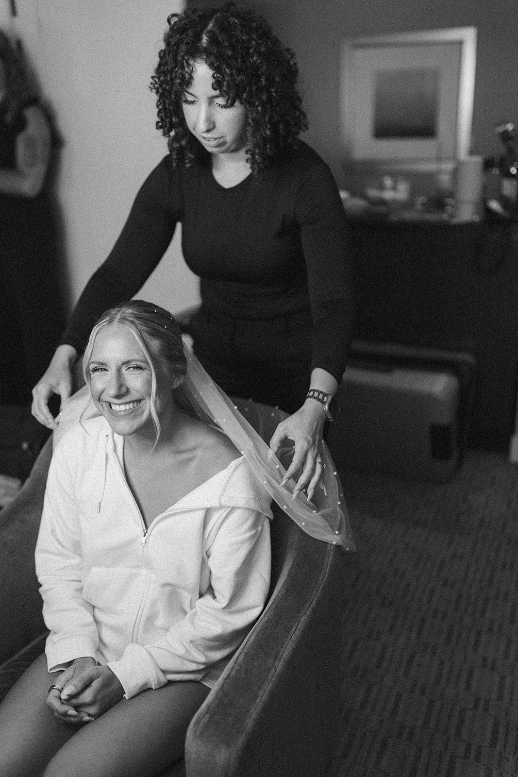 Bride sitting in hair chair while hair and makeup artist gets her ready for her wedding in Wisconsin