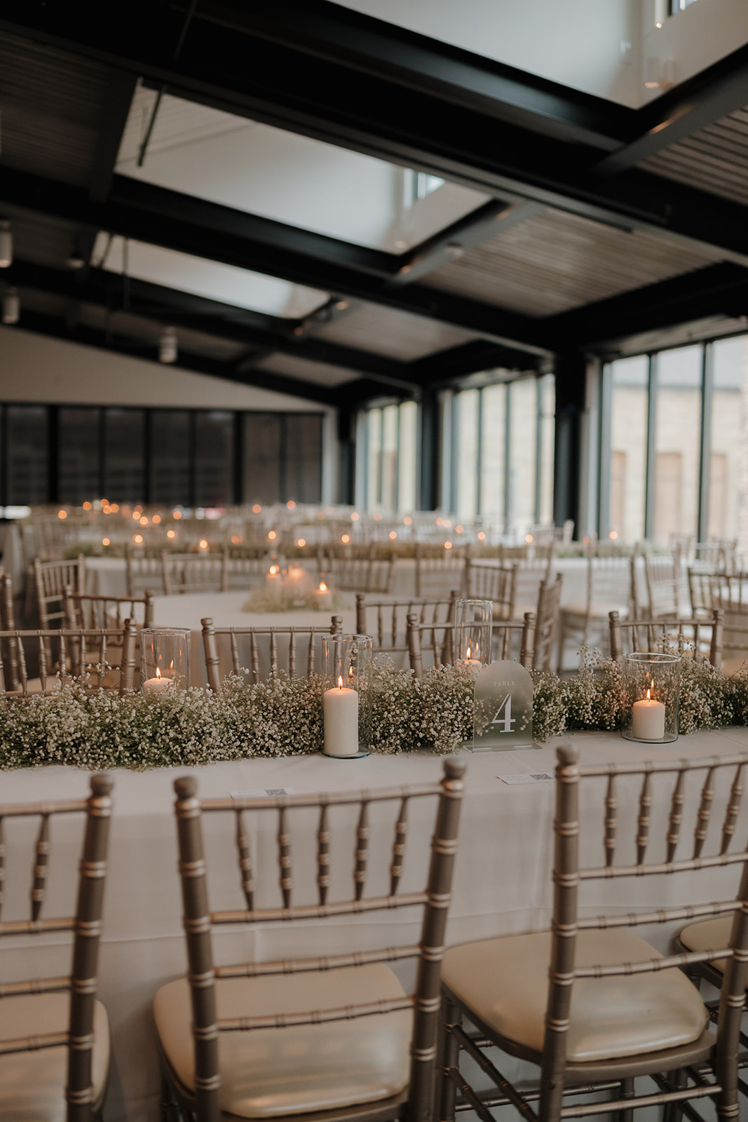 Rows of chairs set up with tables and baby's breath all down the table for their elegant reception