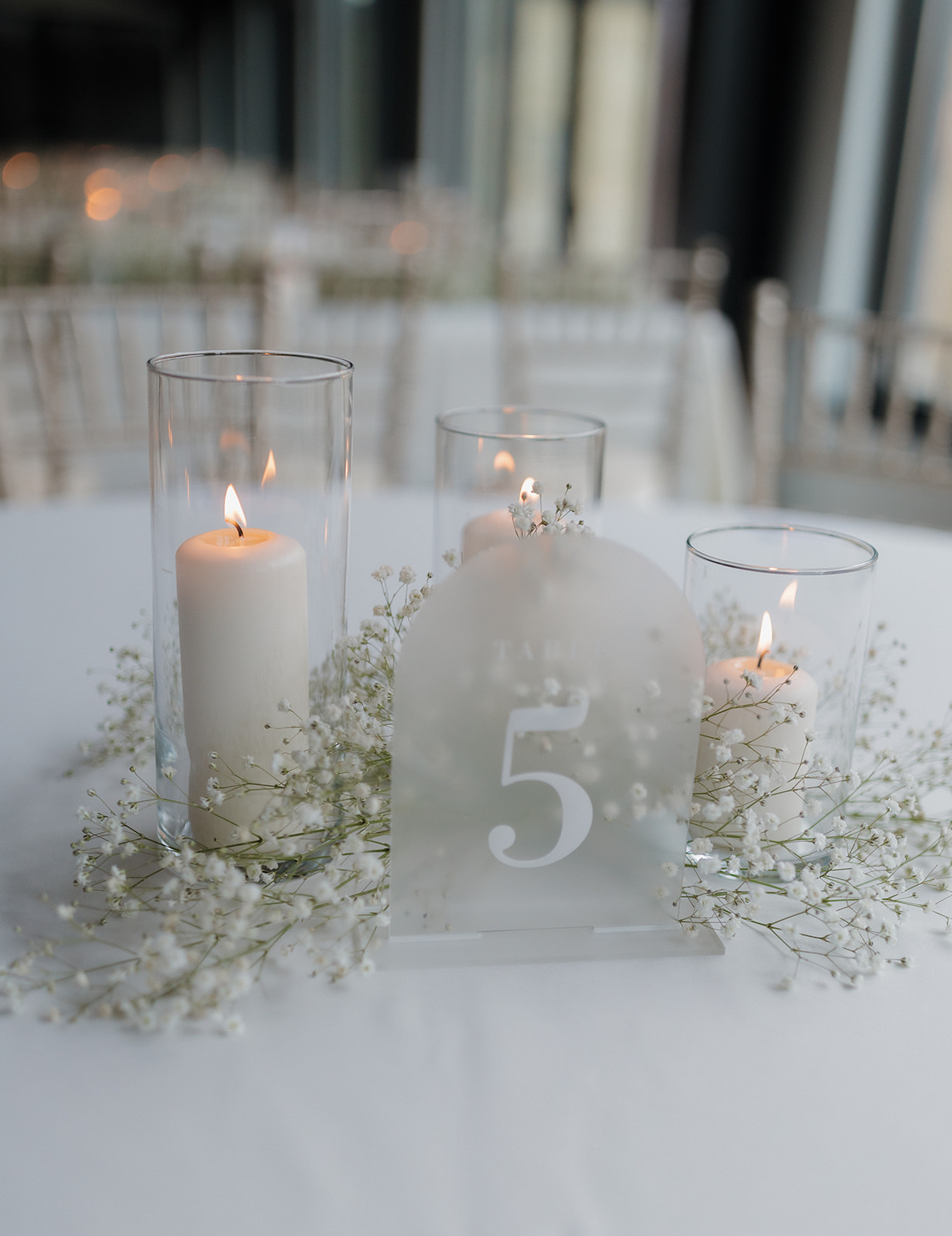 Wedding tablescape with baby's breath, candles and acrylic table number.