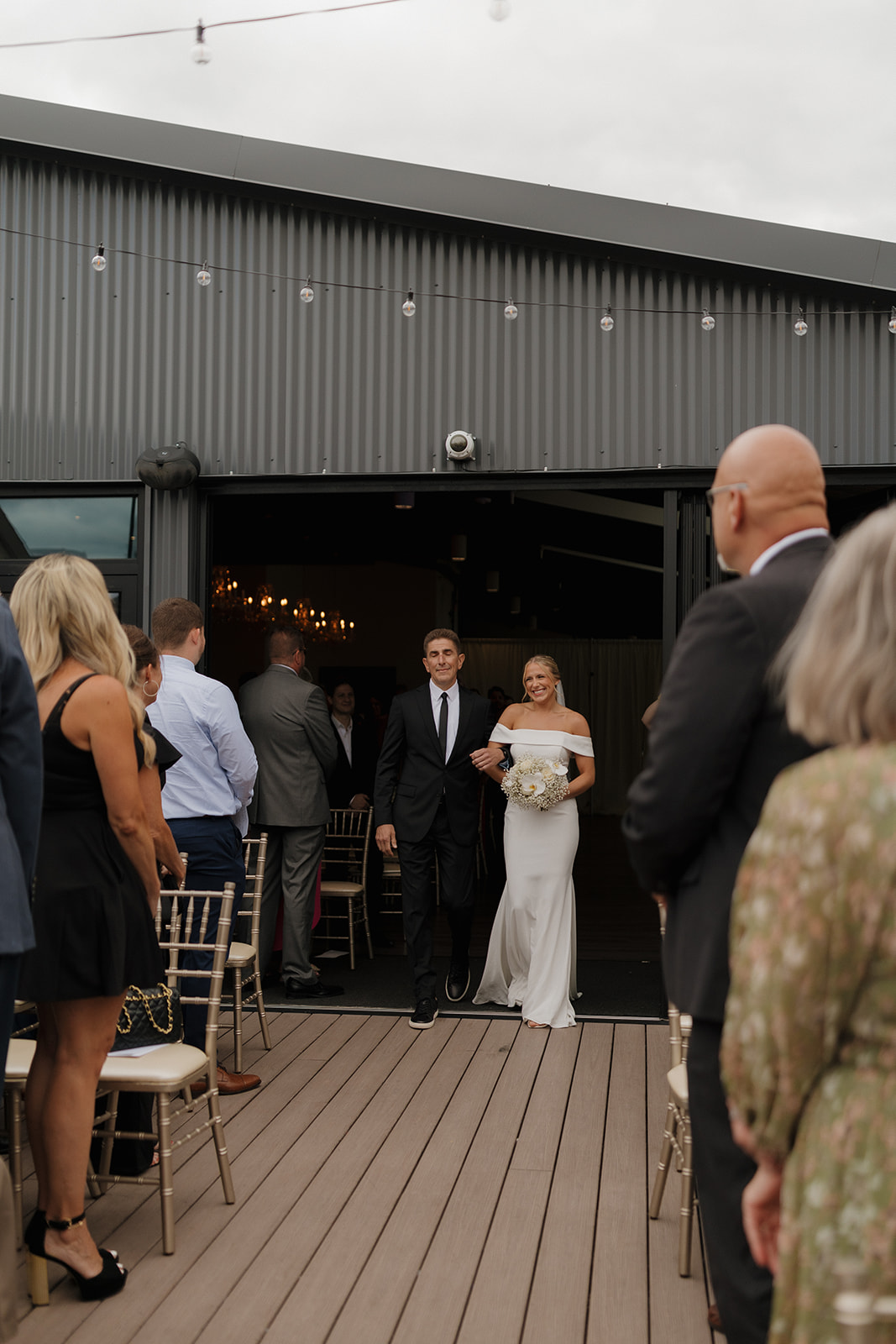 Bride being walked down the aisle by her father in her strapless wedding gown, as guests watch on for her wedding in Wisconsin.