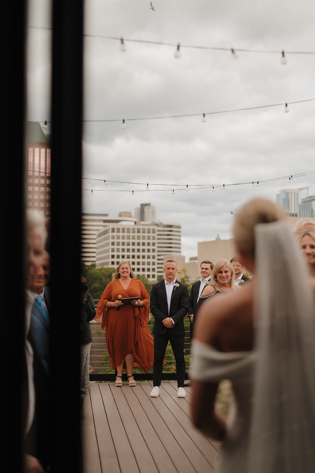 Groom standing at alter watching his bride begin her walk down the aisle with a creative view from her viewpoint.