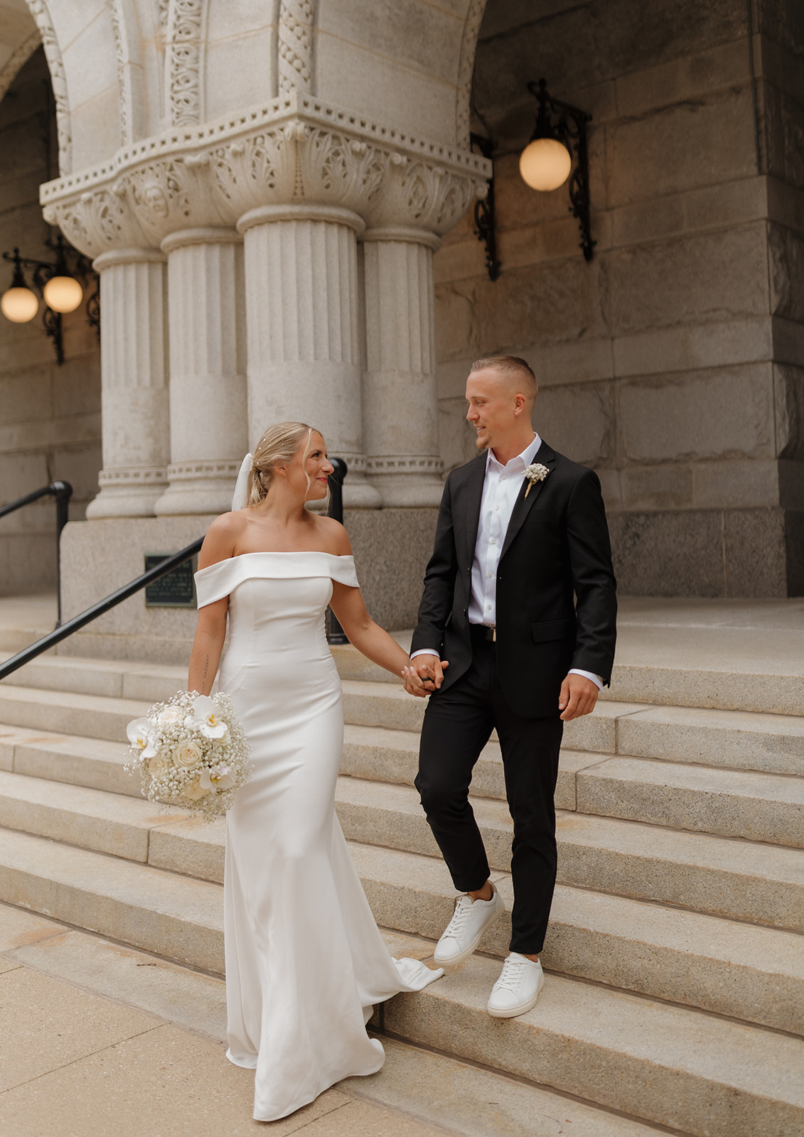 Newly married couple walking hand in hand down the marble staircase after wedding in Wisconsin.