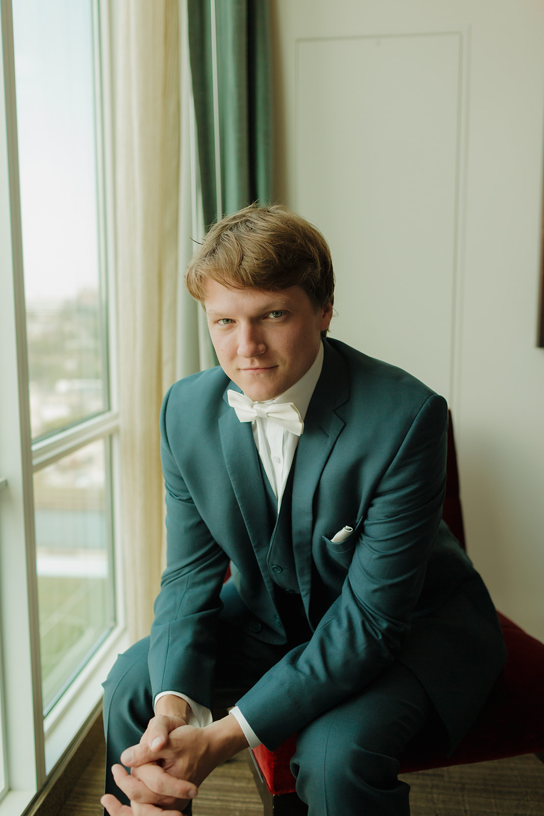 Groom wearing blue suit sitting down before wedding