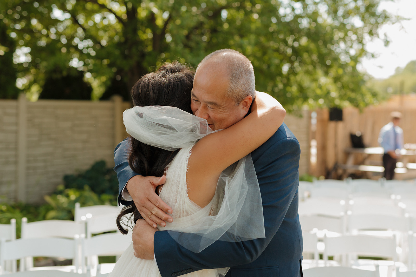 Father of the bride hugs bride after first look before wedding day