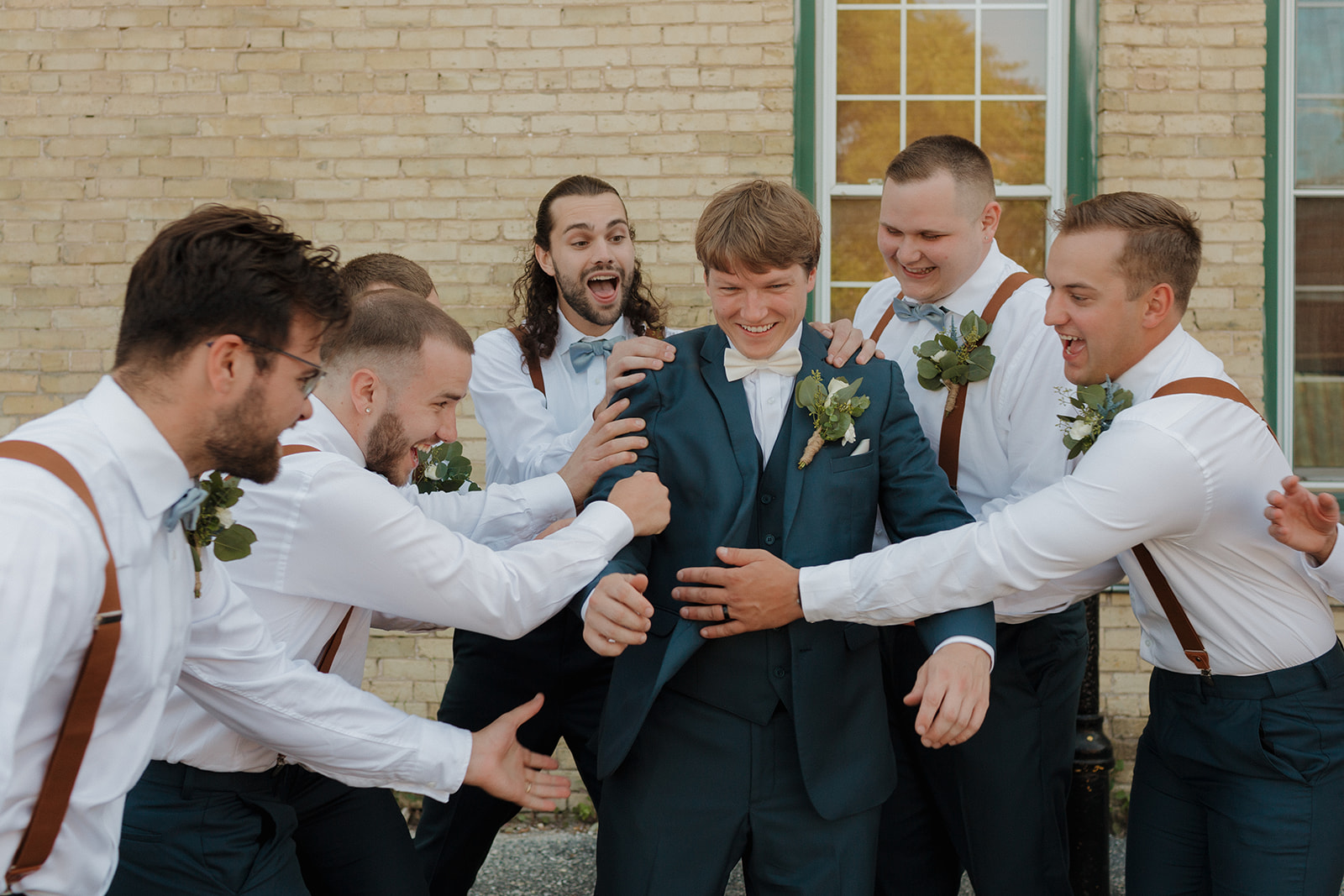 Groomsmen roughhouse with the groom during photos all playing together and being silly