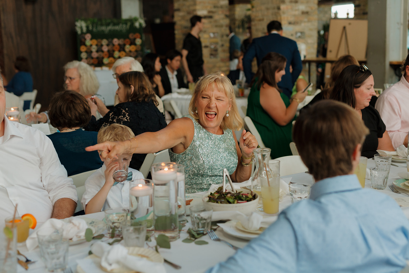 Wedding guest pointing and dancing at dinner table celebrating newly married couple