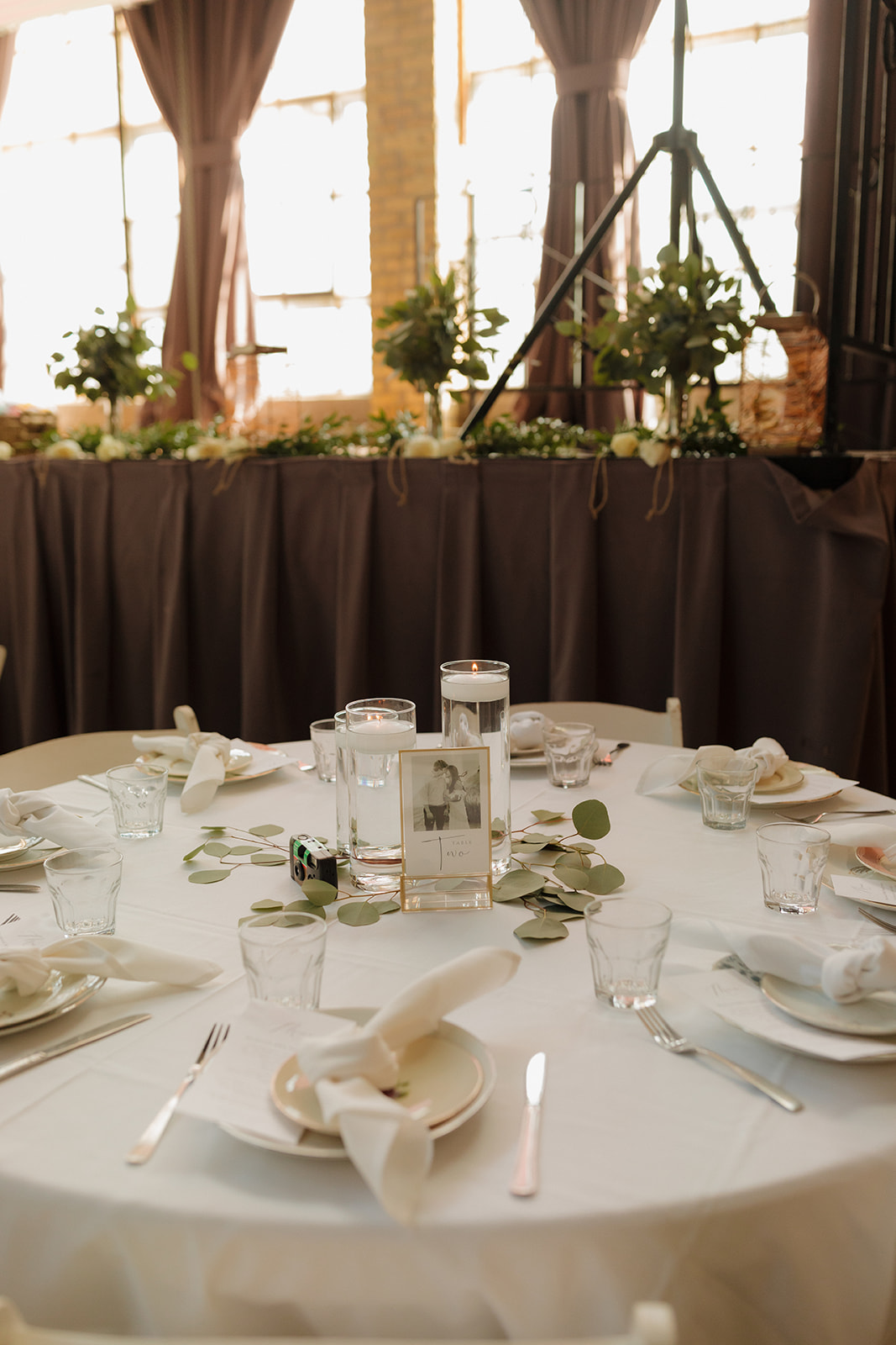 Reception table set with neutral linens, minimalist place settings, and a candlelit centerpiece, photographed inside a Milwaukee wedding venue.