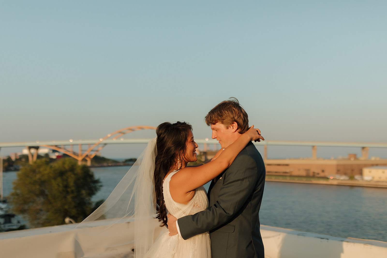 Bride and groom embrace on rooftop after intimate wedding ceremony at Milwaukee wedding venue overlooking cityscape. 