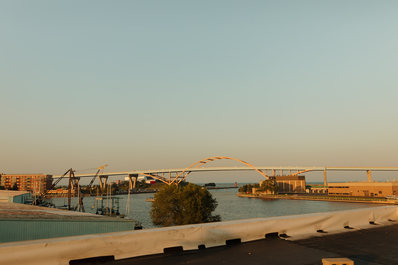 View of the iconic Hoan Bridge from the rooftop of a Milwaukee wedding venue at sunset, with warm tones lighting up the water.