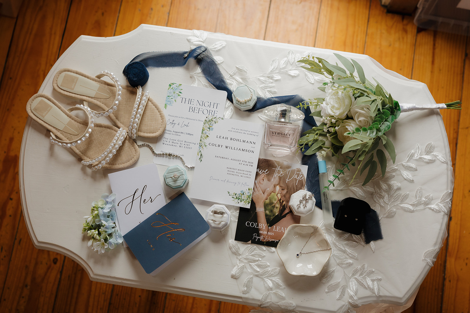 Bridal accessories, vow books, and florals beautifully styled on a lace-covered table.