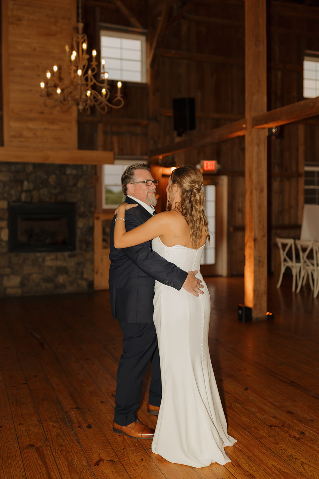 Bride dancing with her father in a cozy, rustic reception space at a Wisconsin wedding venue.