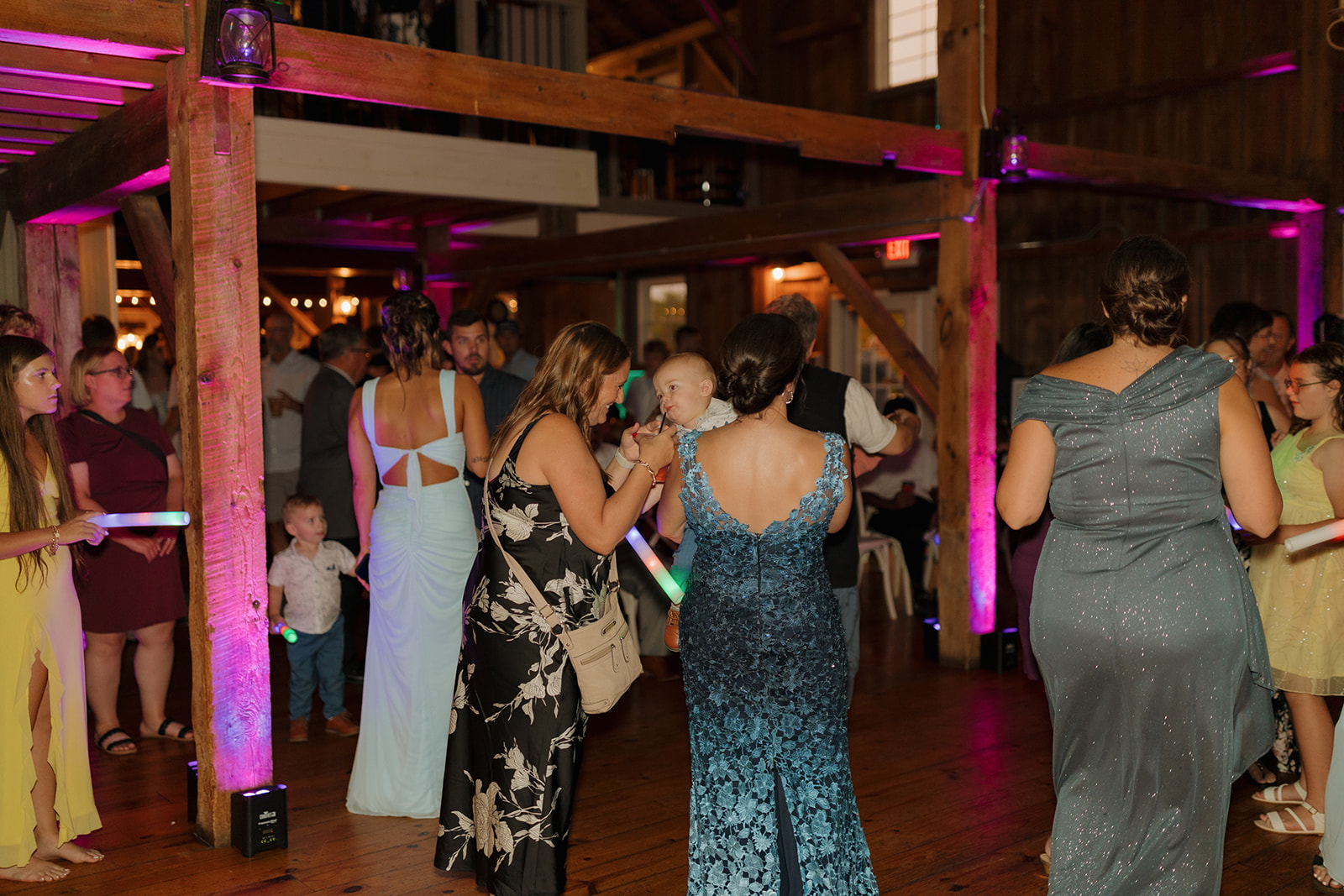 Guests gathered on the dance floor under warm wooden beams and glowing uplighting at a Wisconsin wedding venue.
