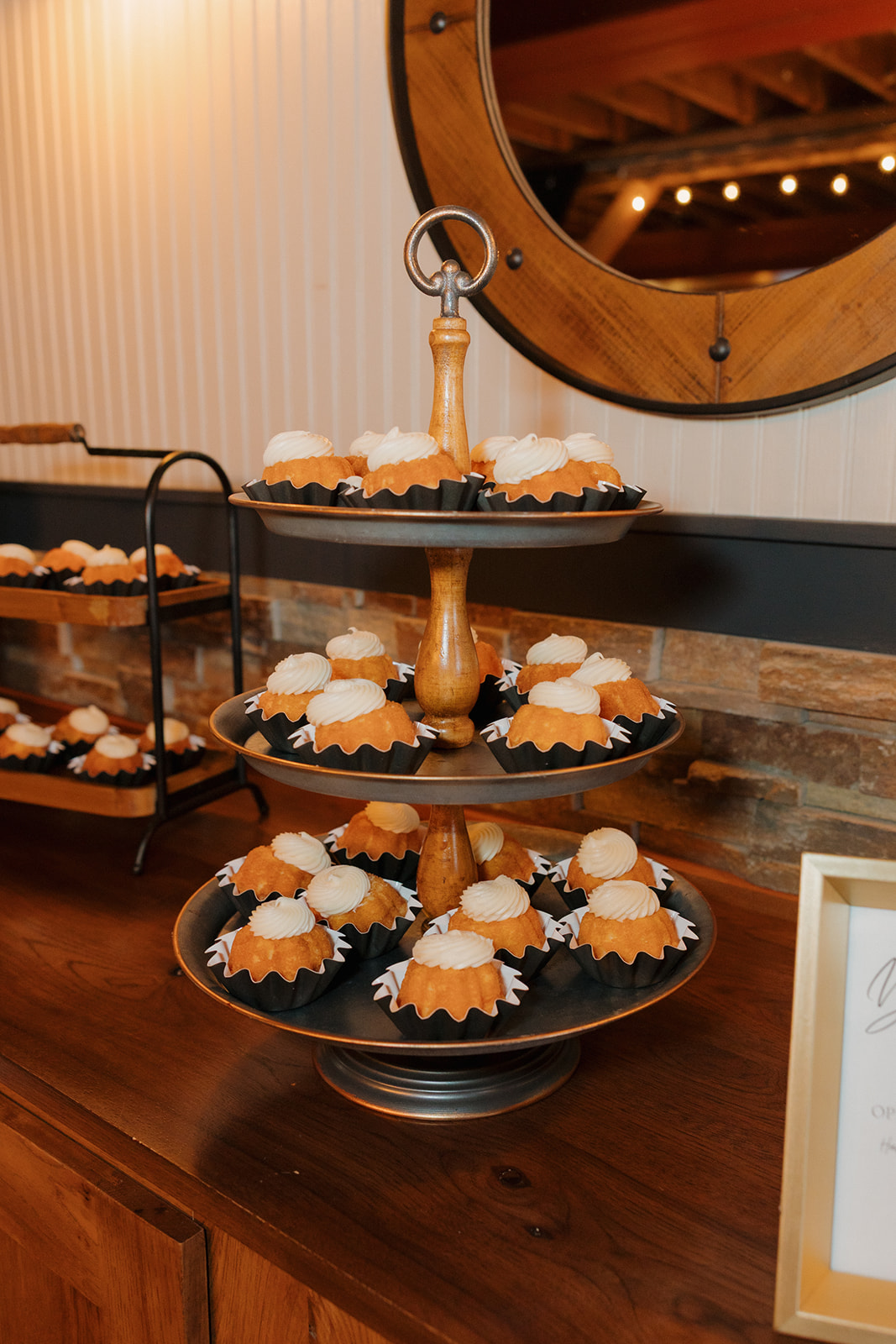 Tiered stand of mini bundt cakes displayed on a dessert table at a cozy indoor reception.