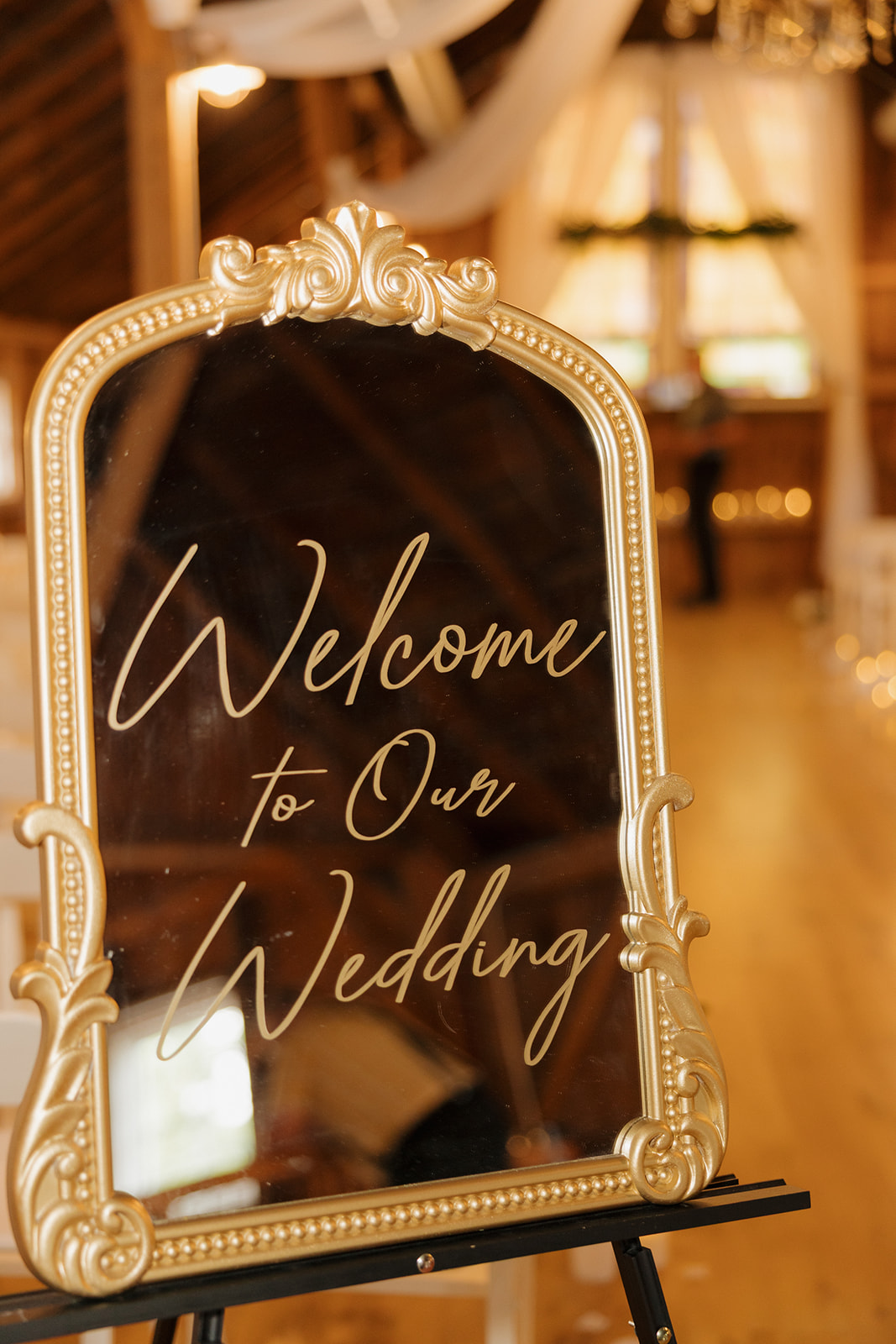 Gold-framed mirror sign with calligraphy reading “Welcome to Our Wedding” inside a Wisconsin wedding venue.