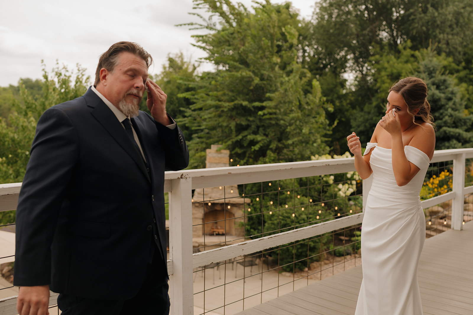 Bride and her father wiping away tears during an emotional first look on the balcony.