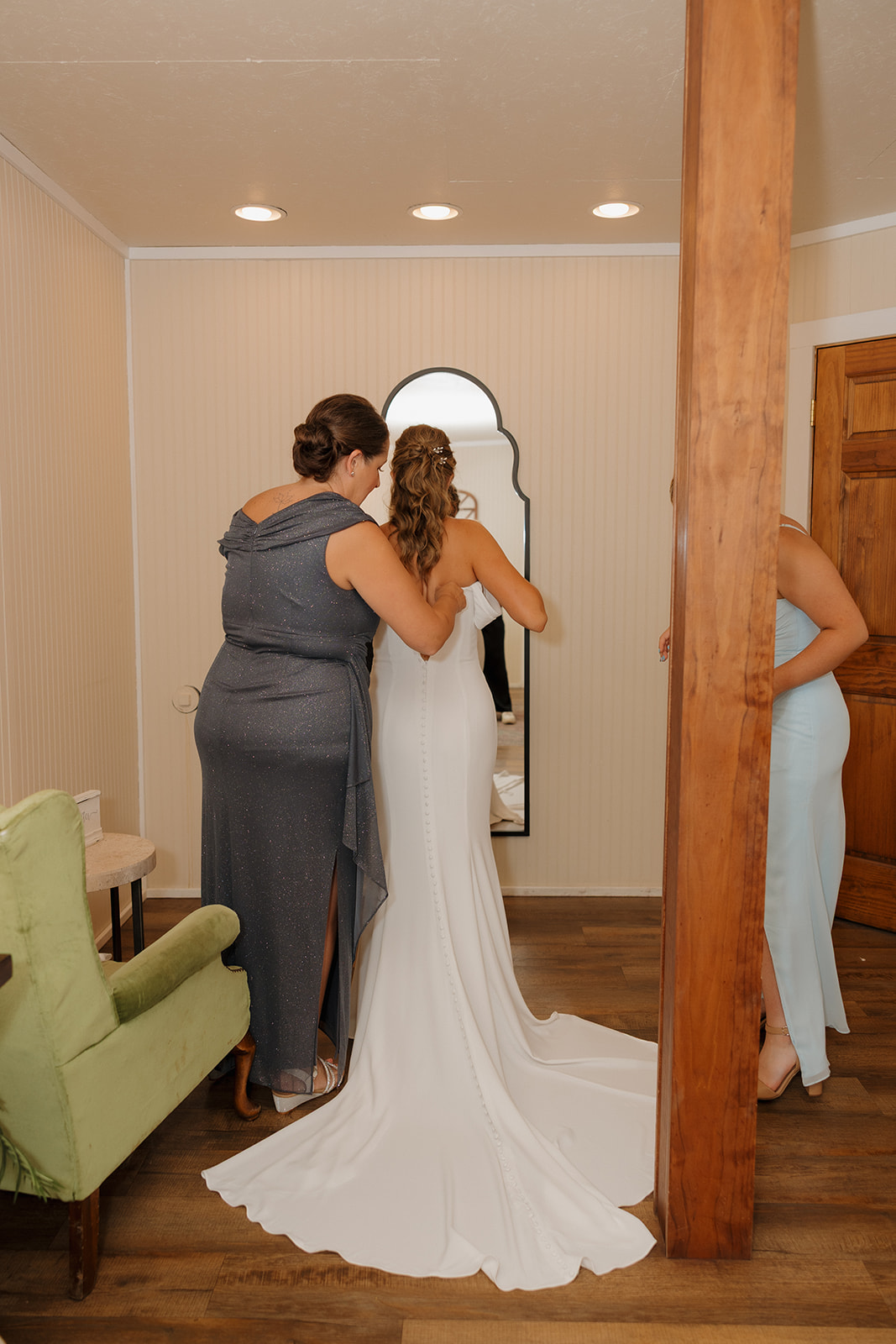 Bride and her mother share a quiet moment while adjusting the dress before the ceremony.
