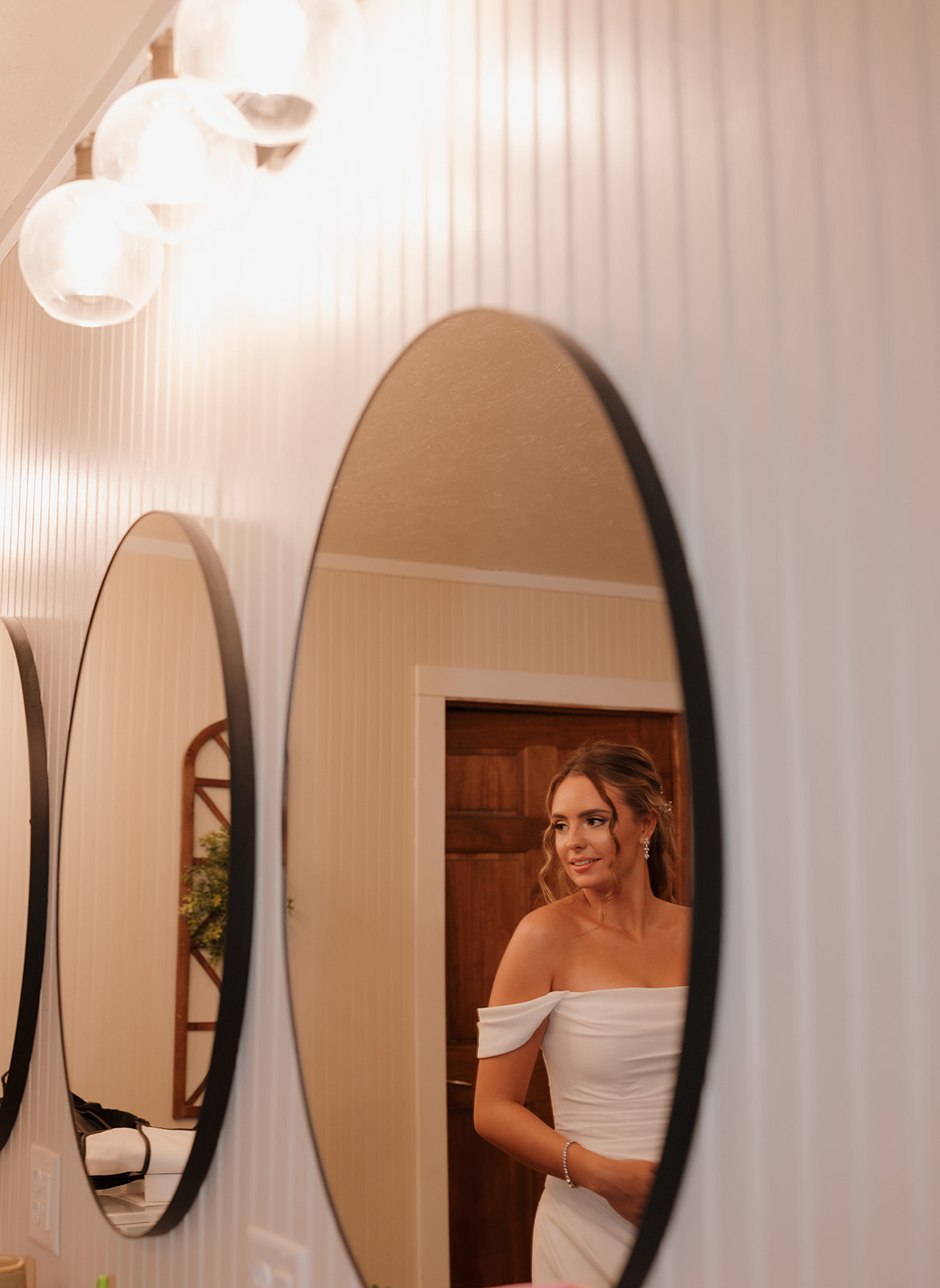 Bride glancing in the mirror with a soft smile before her ceremony at a Wisconsin wedding venue.