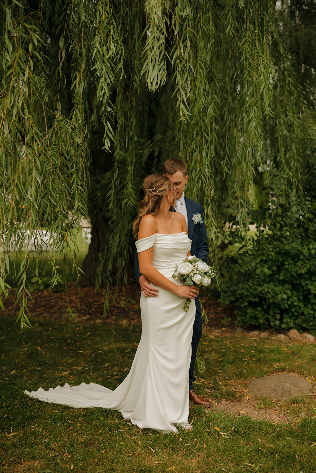 Bride and groom sharing a quiet moment under the canopy of a weeping willow at a Wisconsin wedding venue.