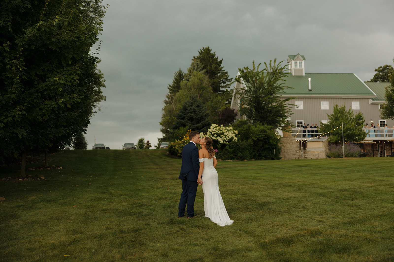 Bride and groom walking across an open lawn toward a charming barn at a Wisconsin wedding venue.