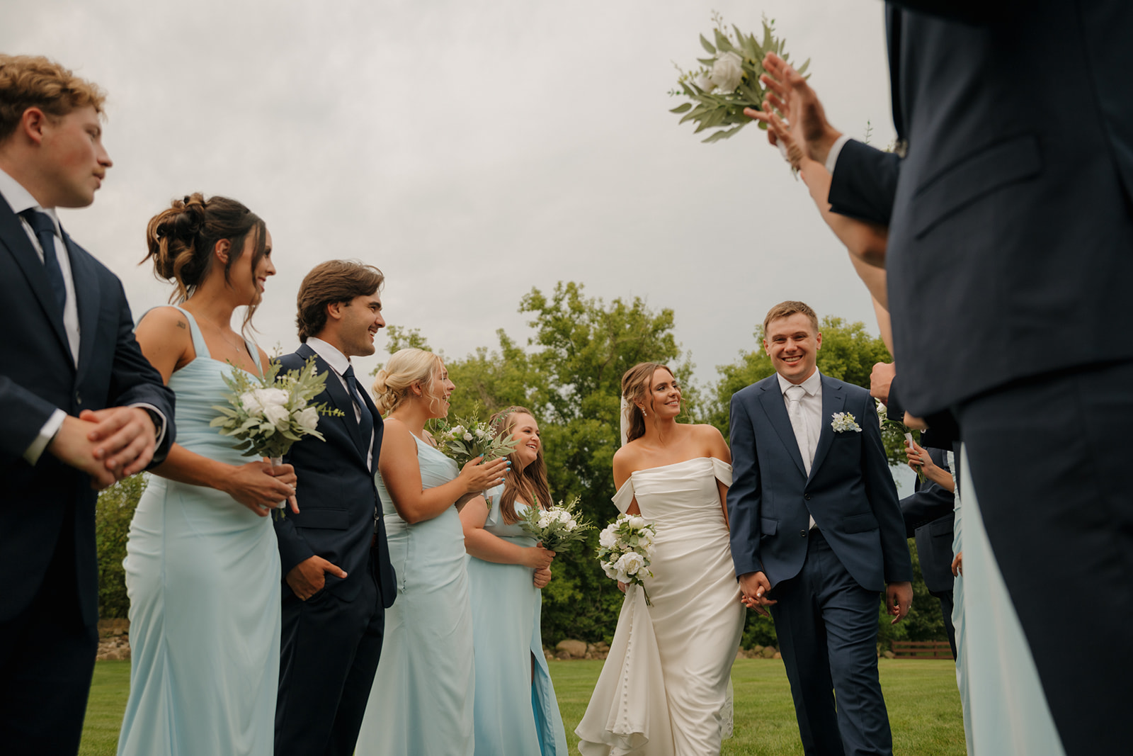 Bride and groom walk hand in hand through a tunnel of cheering wedding party members at a Wisconsin wedding venue.