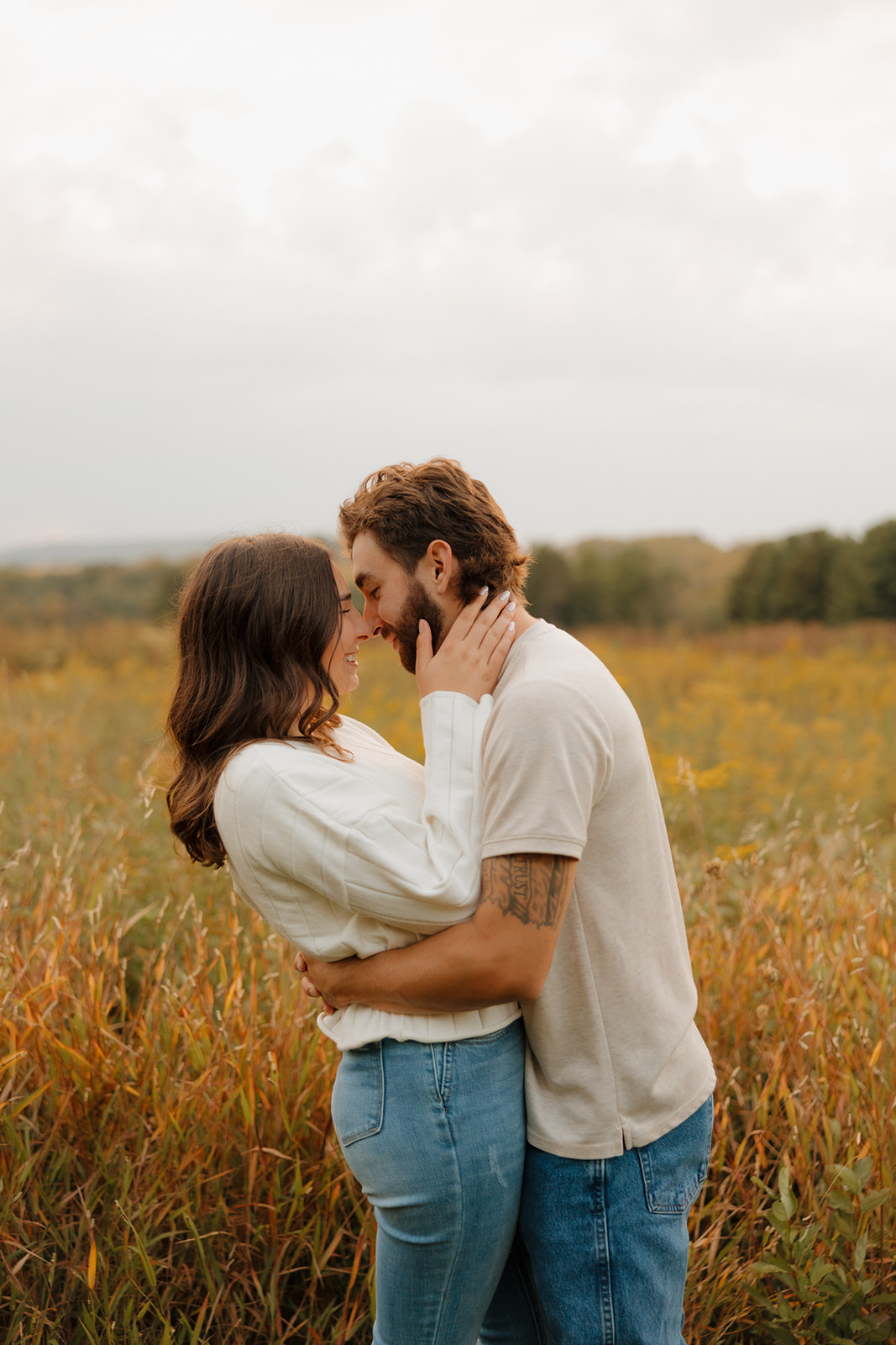 Sweet moment of a couple leaning forehead to forehead in a Madison WI wildflower field, arms wrapped tight.