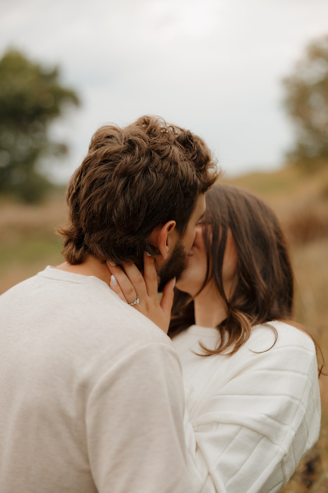 Close-up of a couple sharing a kiss in a field near Madison WI, her hand gently holding his face.
