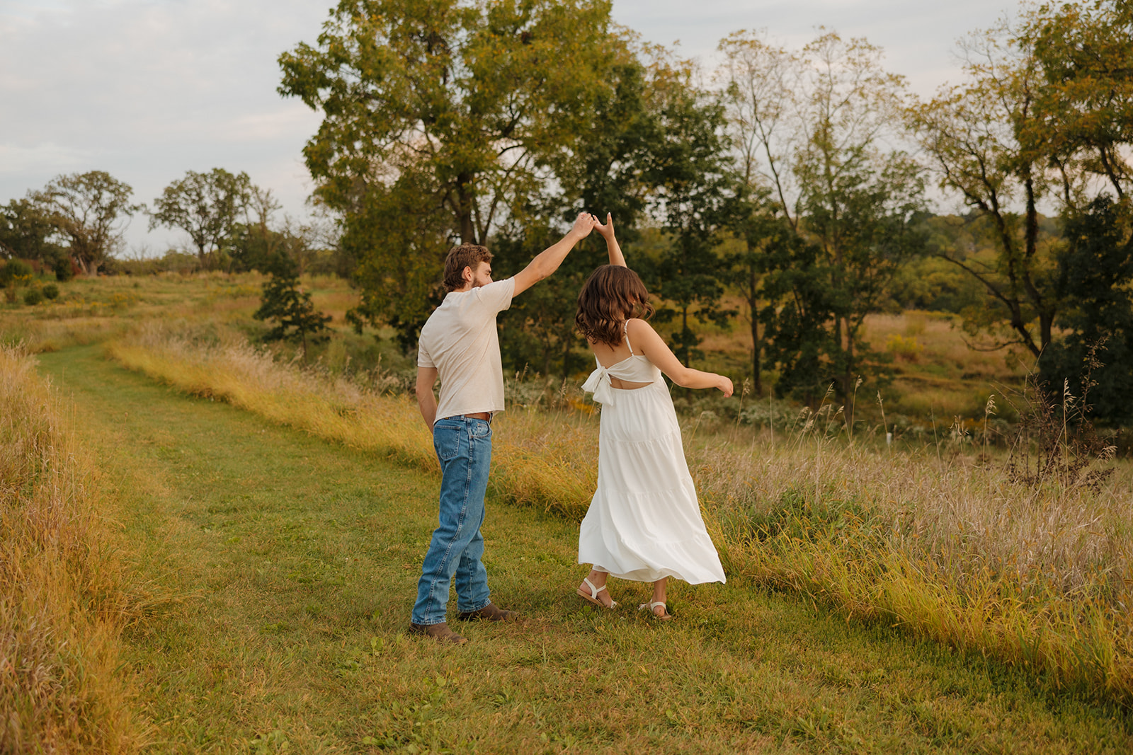 Playful twirl caught mid-spin during an engagement session in a grassy field near Madison WI.
