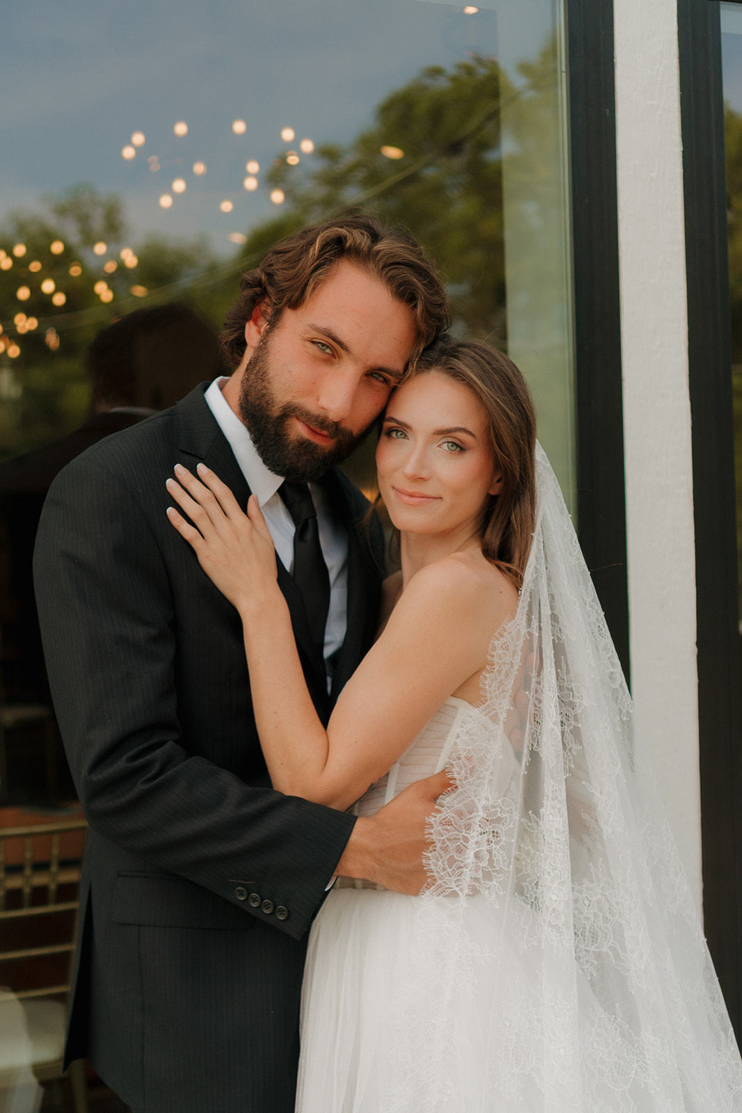 Bride and groom embrace with soft smiles and relaxed elegance outside their venue—capturing the warmth of weddings in Wisconsin.