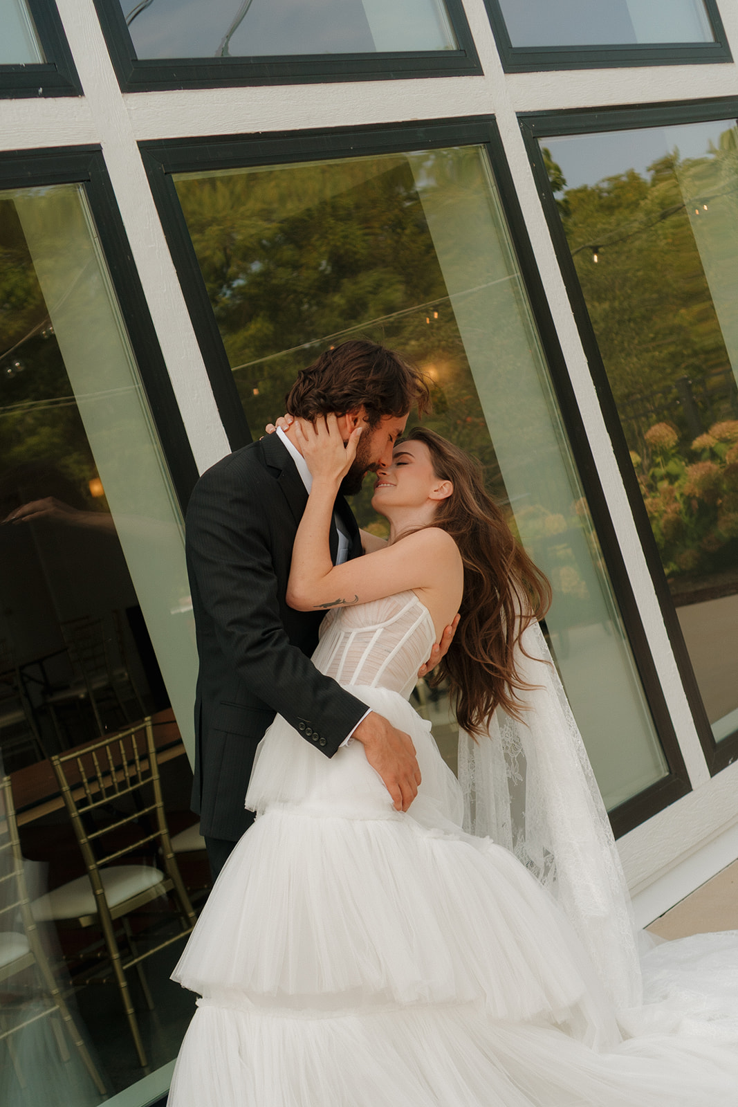 Tender outdoor moment as the groom rests his forehead on his bride’s, her veil catching the breeze—pure love on display at weddings in Wisconsin.