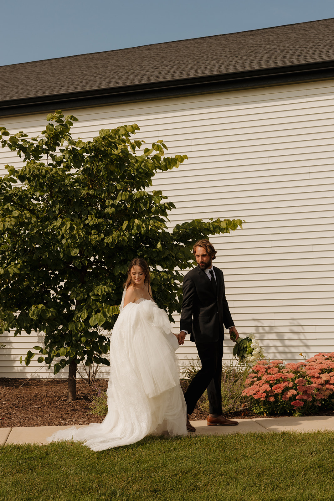 The couple shares a kiss in a romantic indoor ceremony space, surrounded by florals, gold lanterns, and soft lighting.